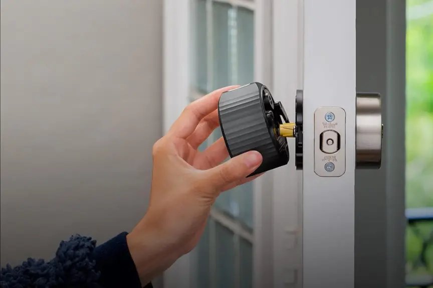 一只手握住安装在白色门上的 August Home Smart Lock 4。