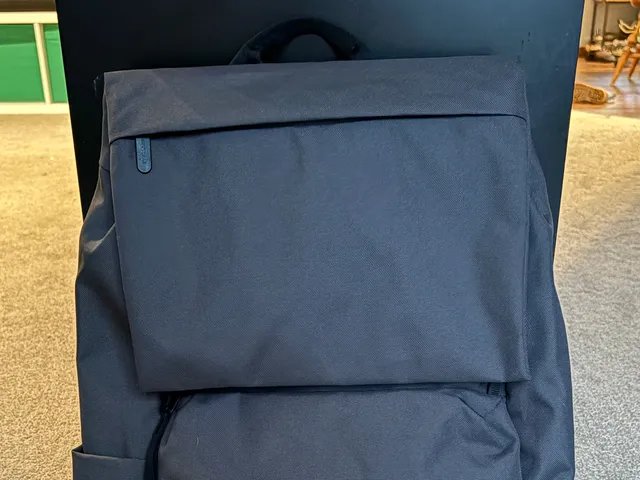 Everlane ReNew Transit 背包的前视图，一个带黑色肩带的灰色包和一个简单的拉链包